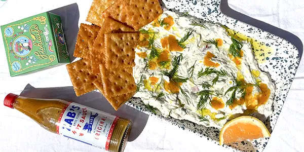 dip and crackers next to a bottle of Zab's hot sauce