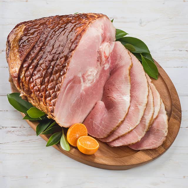 Spiral ham on platter with oranges and herbs