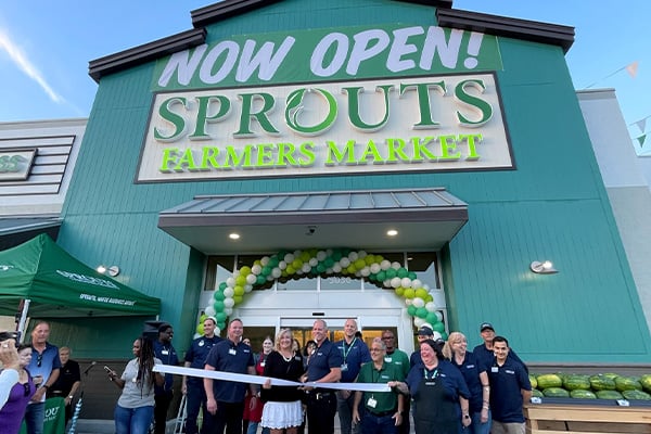 sprouts storefront with Now Open sign and people doing a ribbon cutting