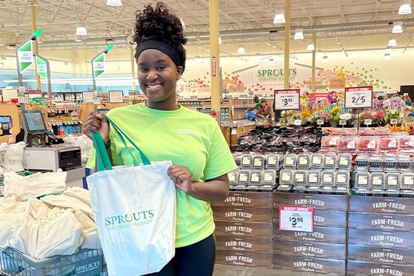Sprouts associate holding gift bags to give away