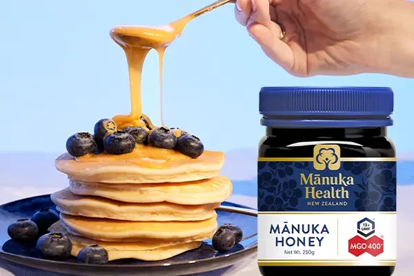 Manuka honey next to a stack of pancakes